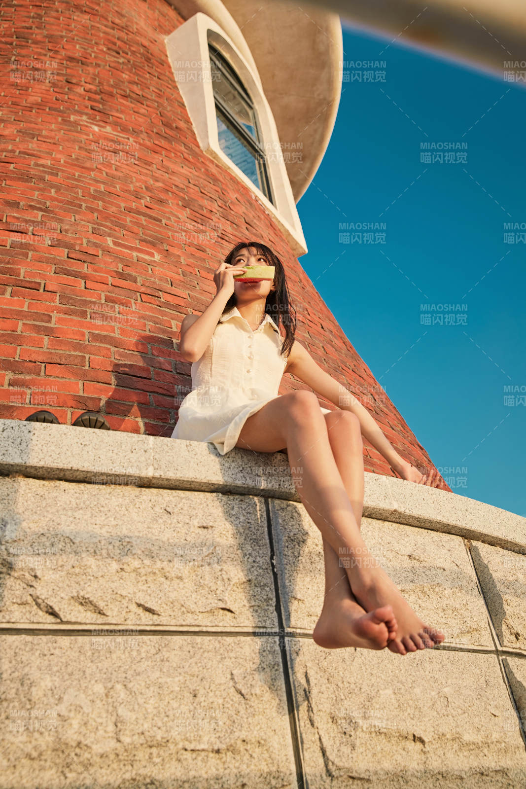 盛夏夕陽湖邊碼頭燈塔上吃西瓜的少女