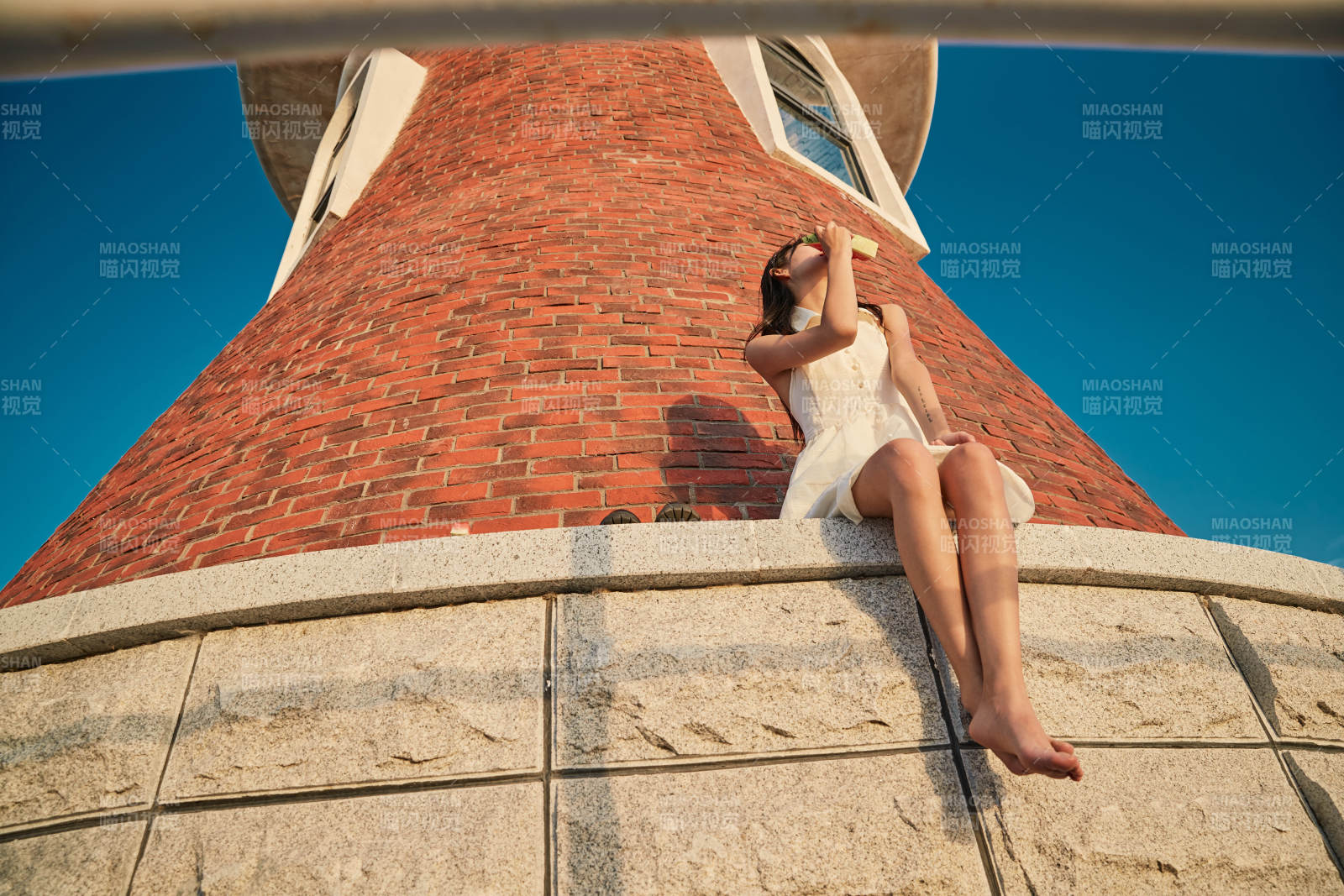 盛夏夕陽湖邊碼頭燈塔上吃西瓜的少女