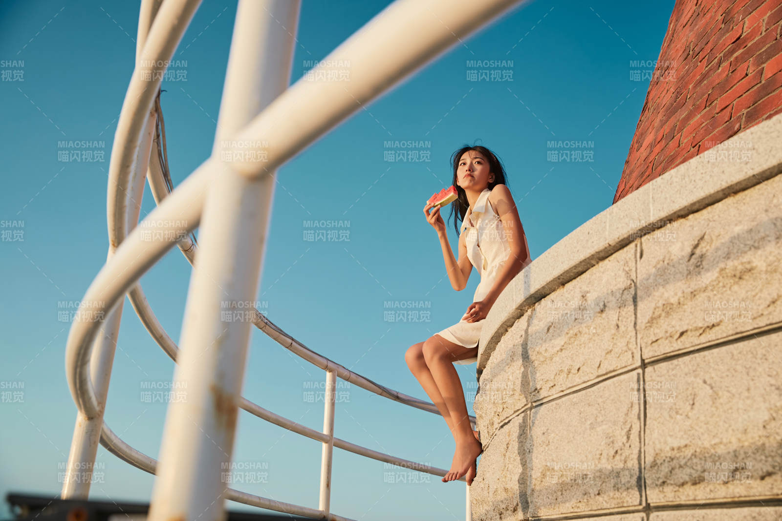 盛夏夕陽湖邊碼頭燈塔上吃西瓜的少女