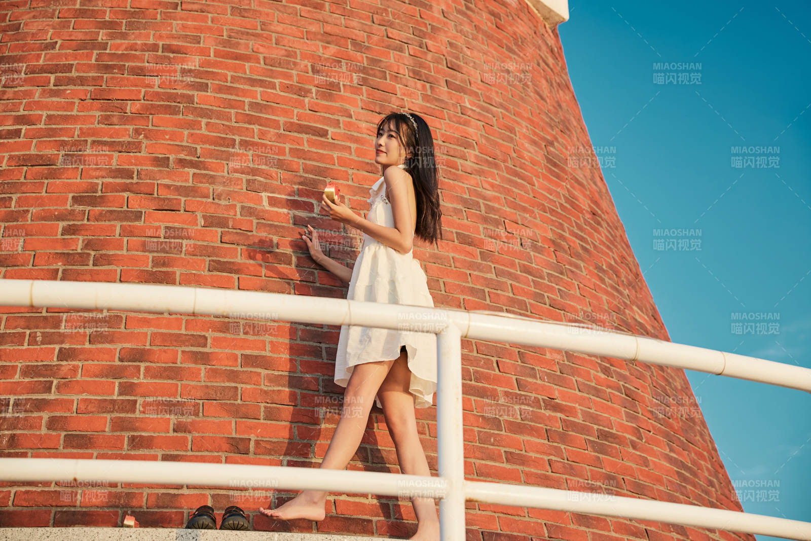 盛夏夕陽湖邊碼頭燈塔上吃西瓜的少女