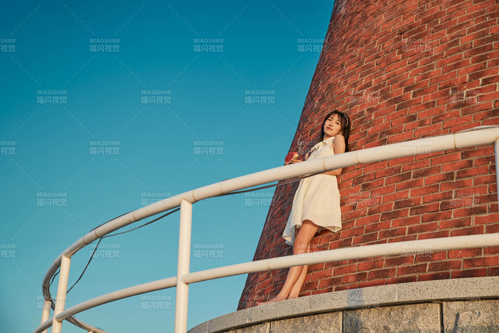 盛夏夕陽湖邊碼頭燈塔上吃西瓜的少女