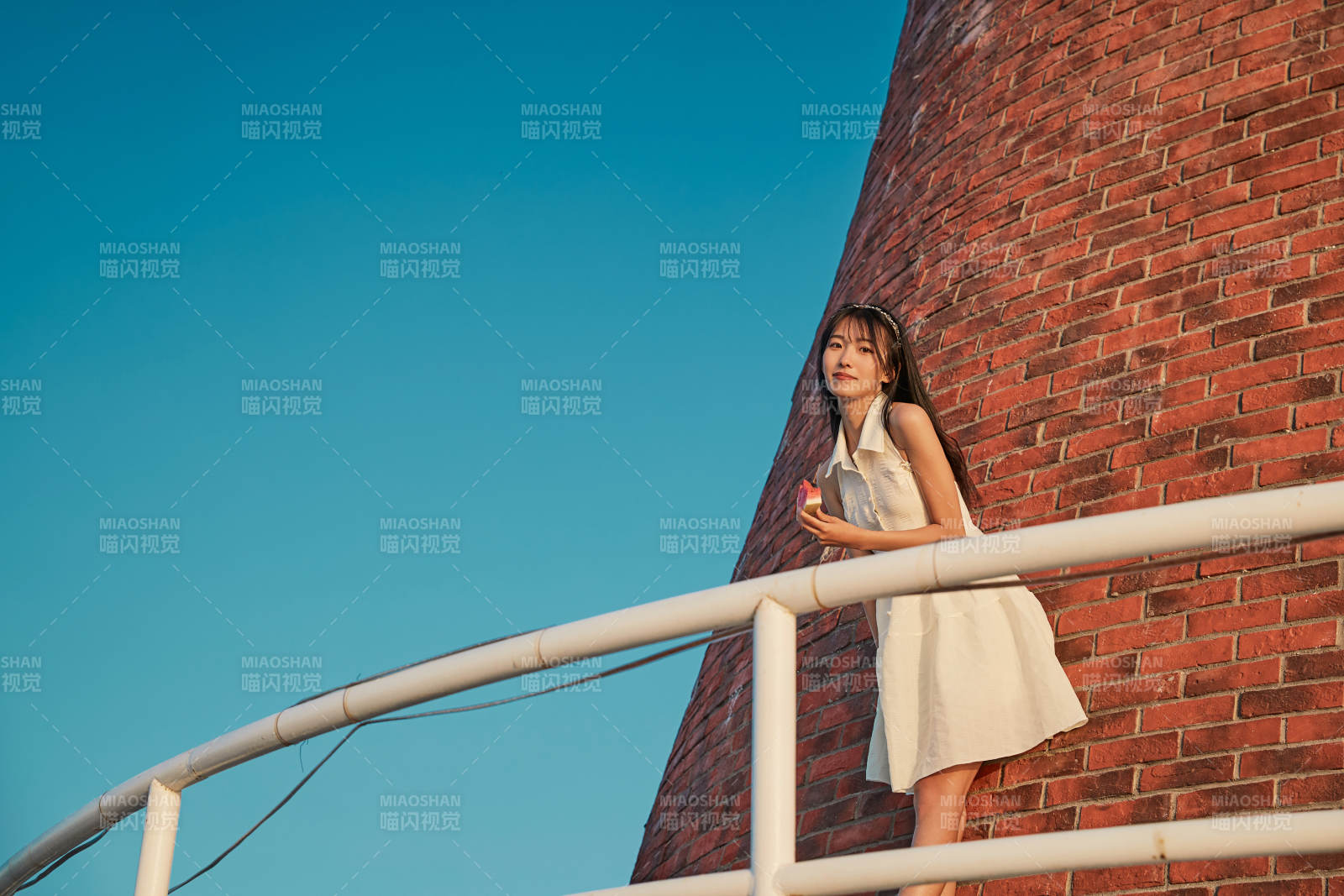 盛夏夕陽湖邊碼頭燈塔上吃西瓜的少女