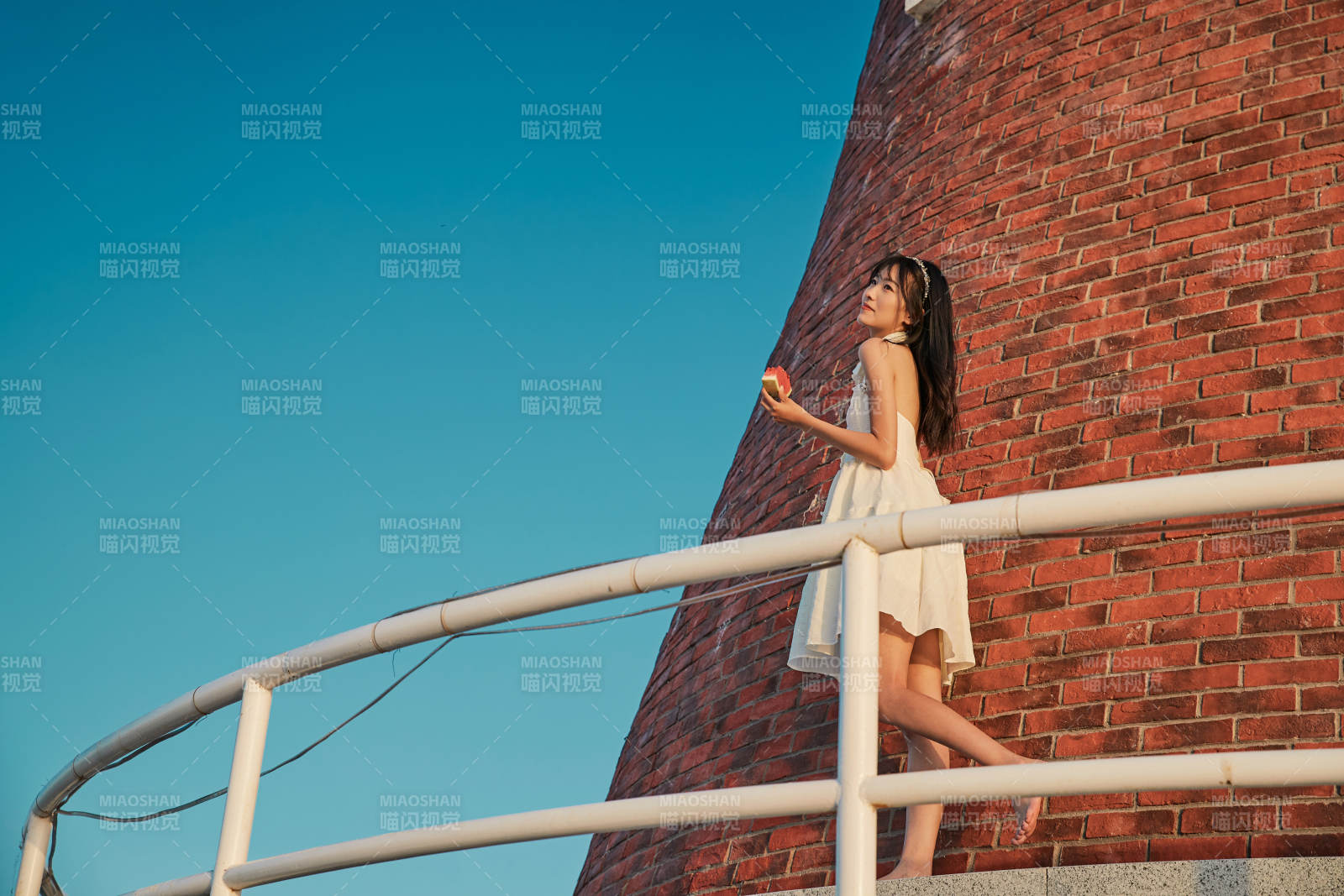 盛夏夕陽(yáng)湖邊碼頭燈塔上吃西瓜的少女