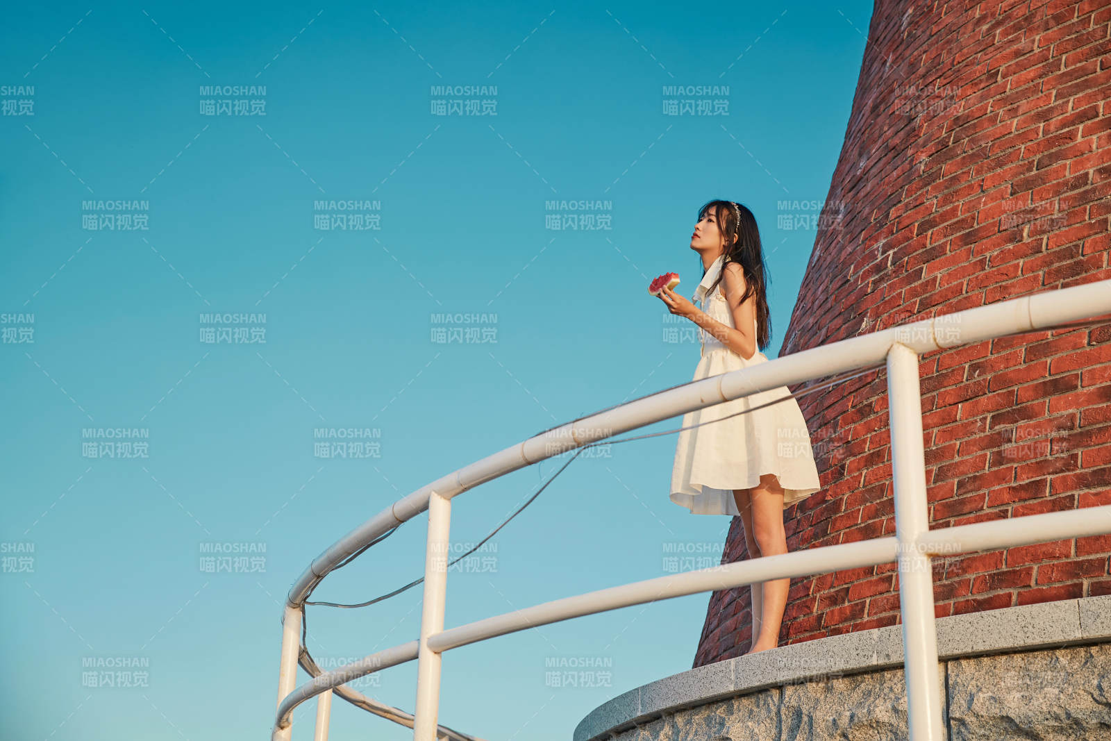 盛夏夕陽湖邊碼頭燈塔上吃西瓜的少女