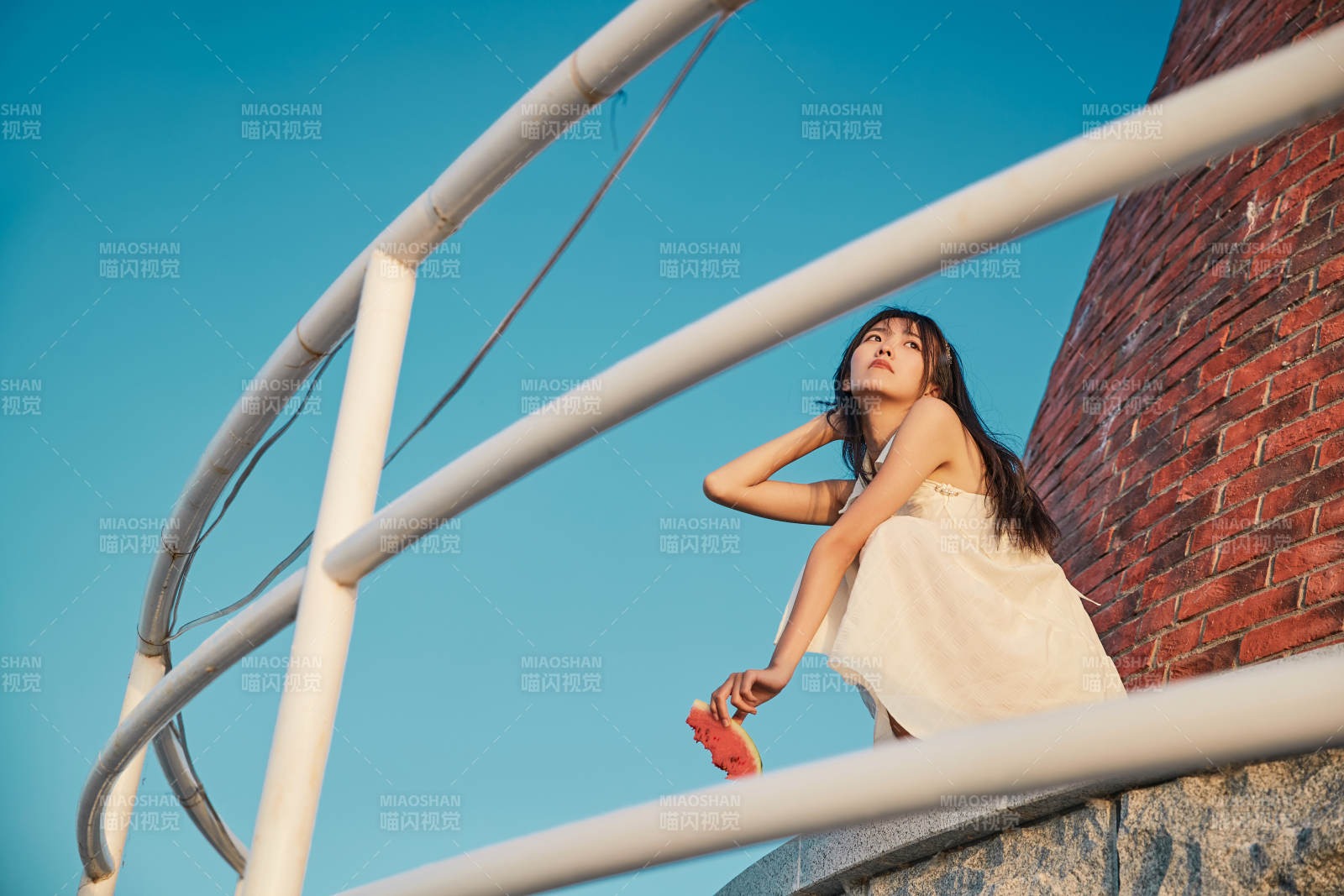 盛夏夕阳湖边码头灯塔上吃西瓜的少女