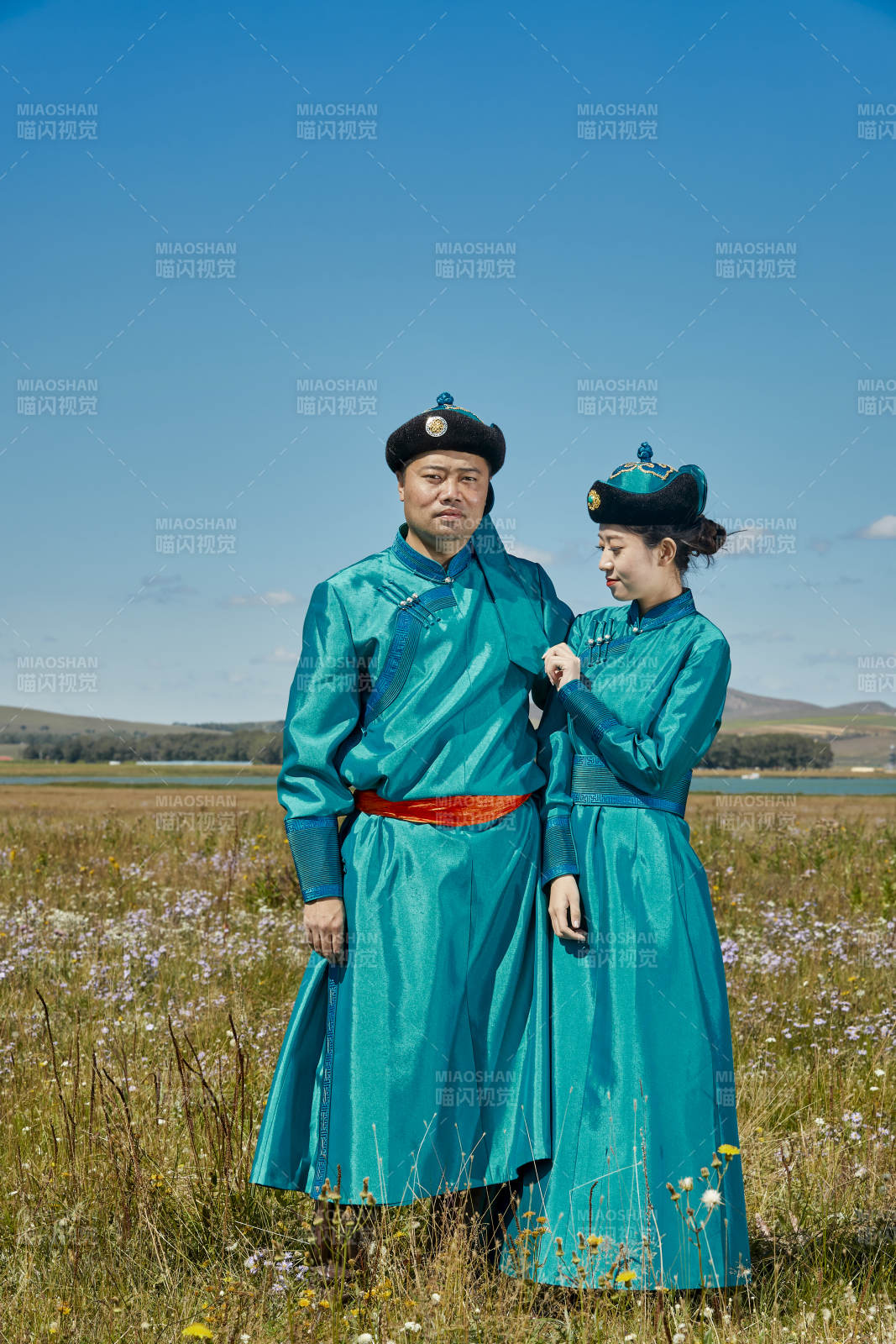 草原上蒙古包前穿蒙古族傳統服飾的年輕夫妻