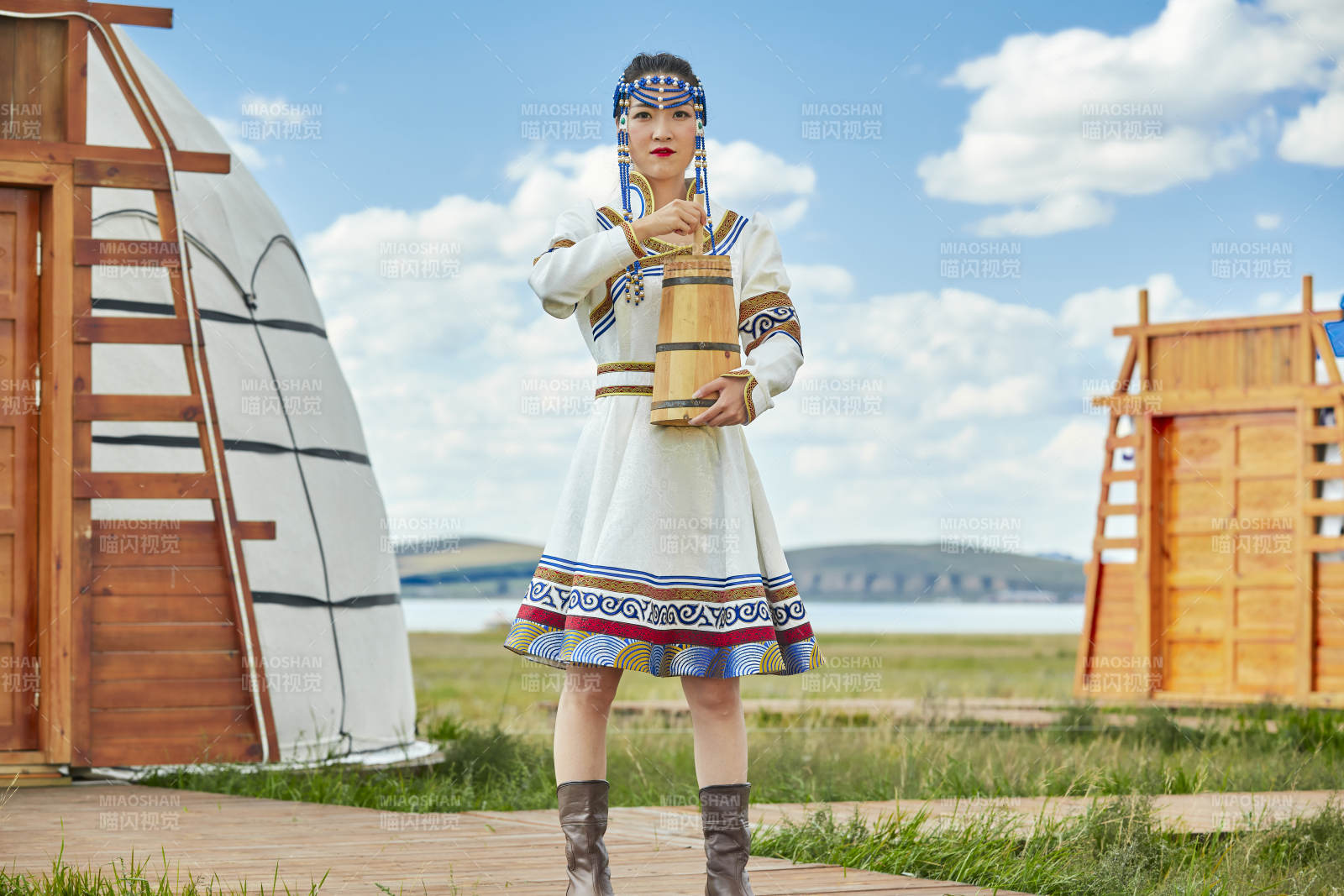 蒙古包前穿蒙古族飾懷抱奶茶桶的蒙族少女