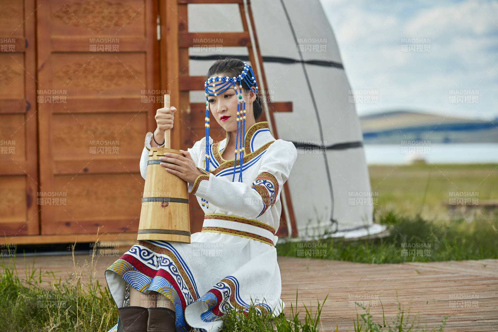 蒙古包前穿蒙古族飾懷抱奶茶桶的蒙族少女