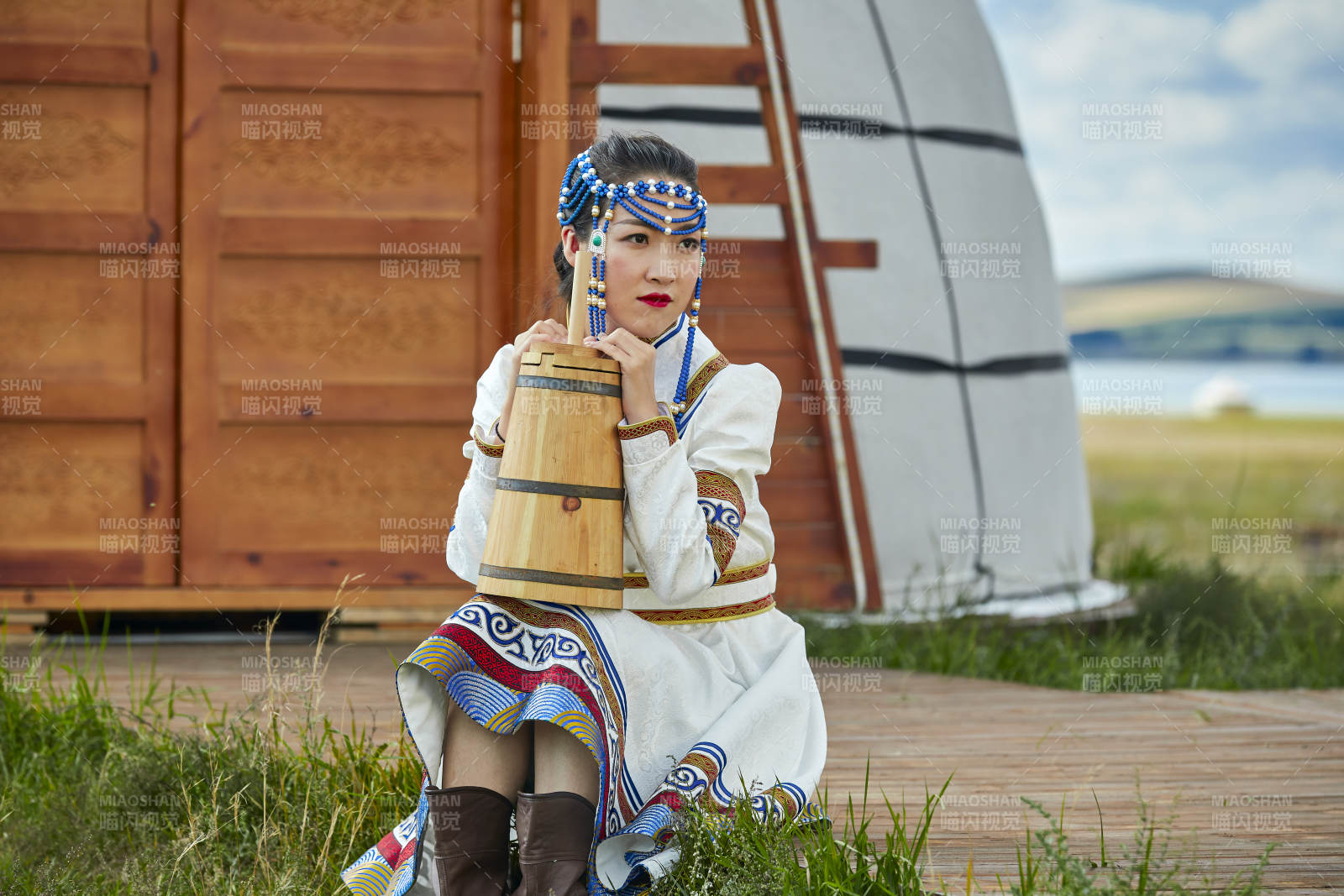蒙古包前穿蒙古族飾懷抱奶茶桶的蒙族少女