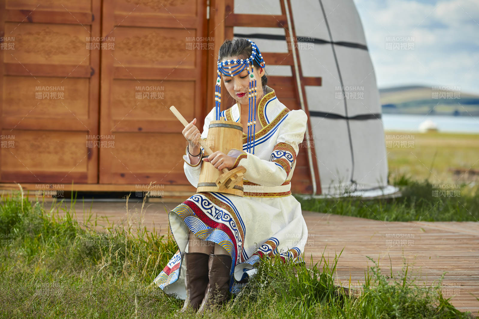 蒙古包前穿蒙古族飾懷抱奶茶桶的蒙族少女