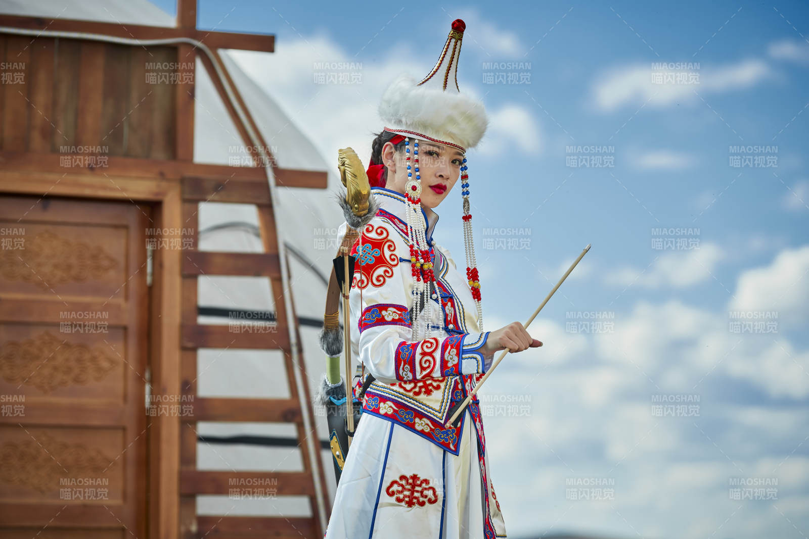 草原湖畔身穿蒙古族飾手持弓箭的蒙族少女