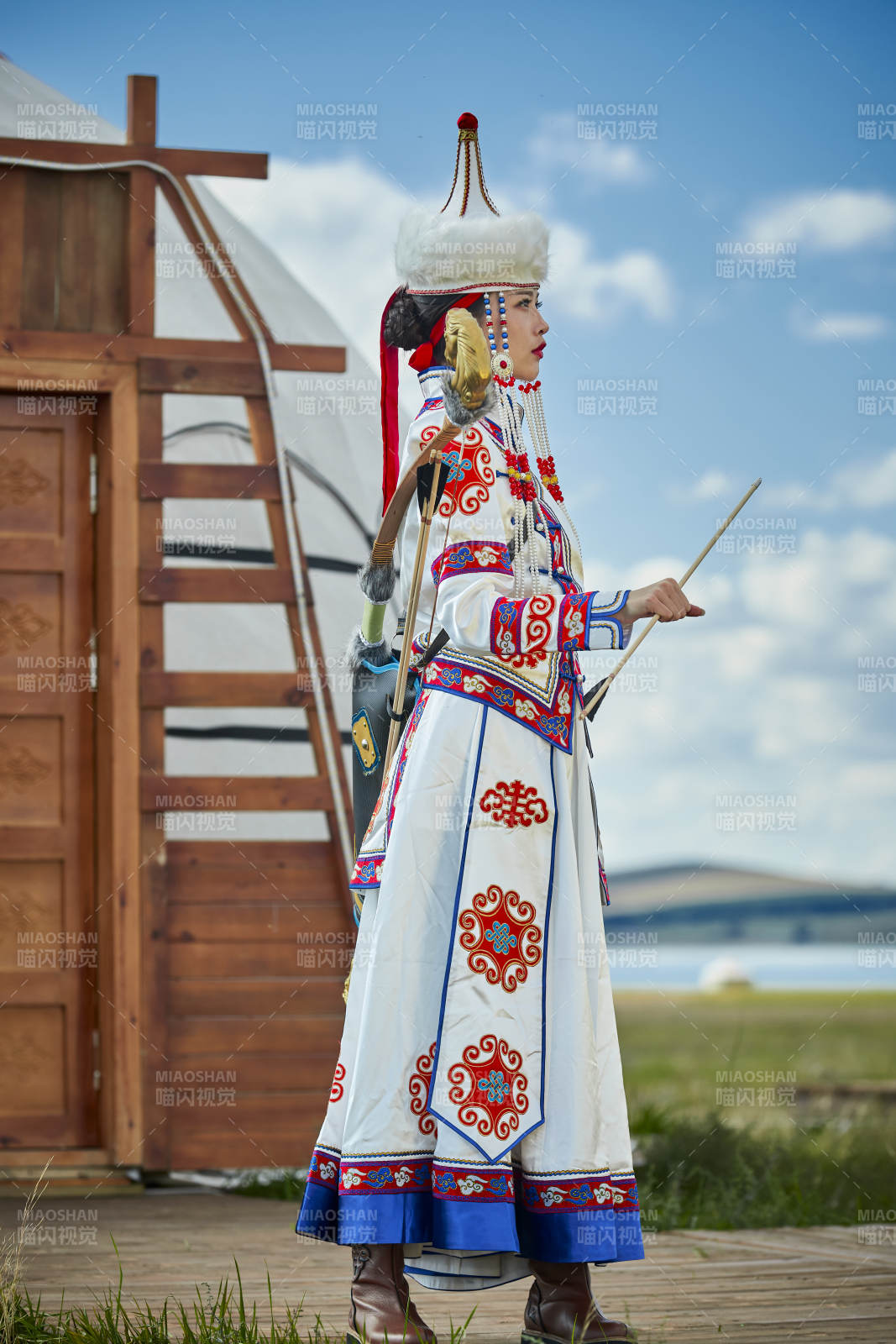 草原湖畔身穿蒙古族飾手持弓箭的蒙族少女