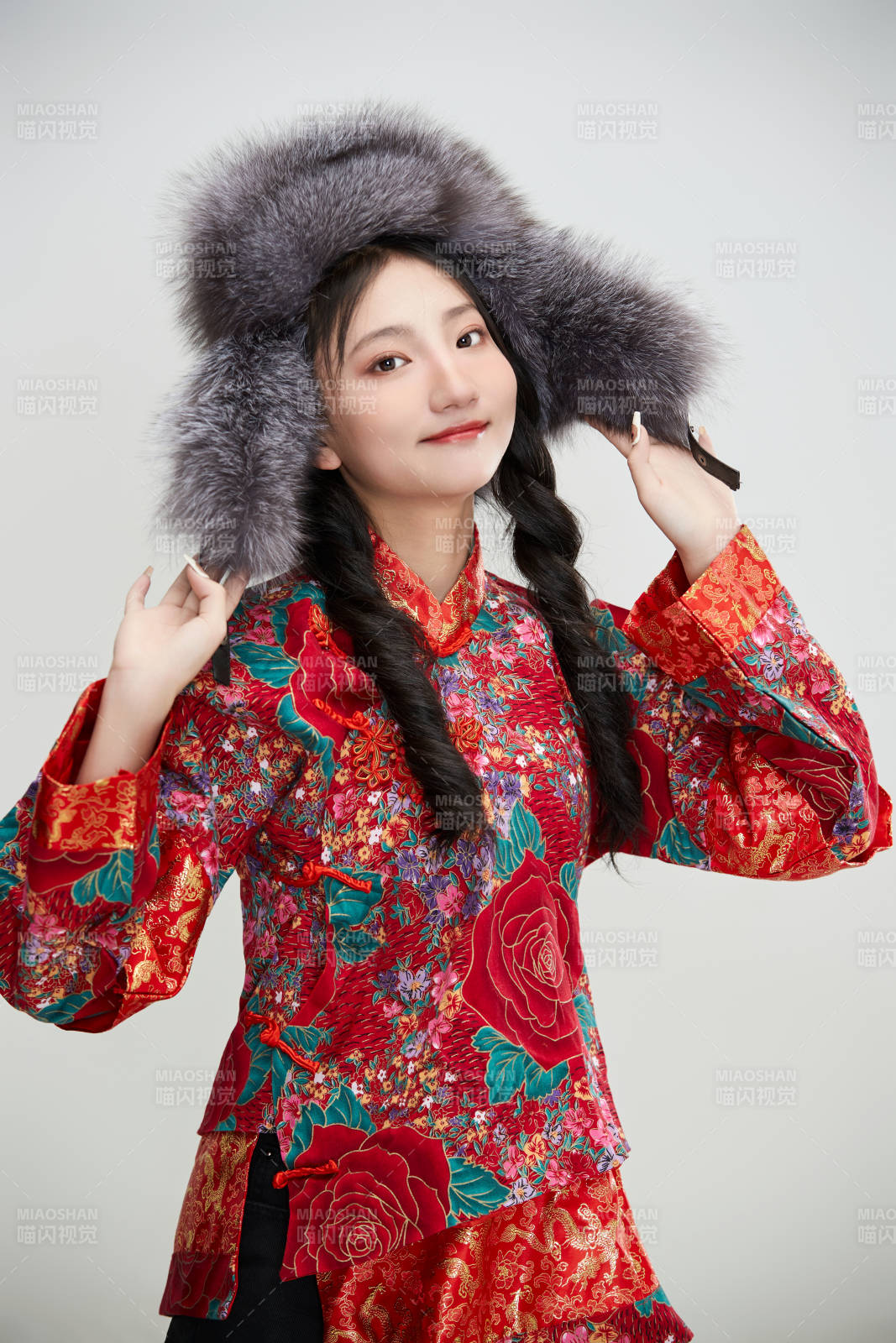 白色背景下穿中國傳統服飾頭戴絨帽的少女