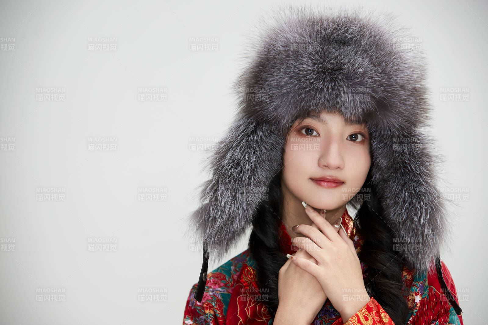 白色背景下穿中國傳統服飾頭戴絨帽的少女