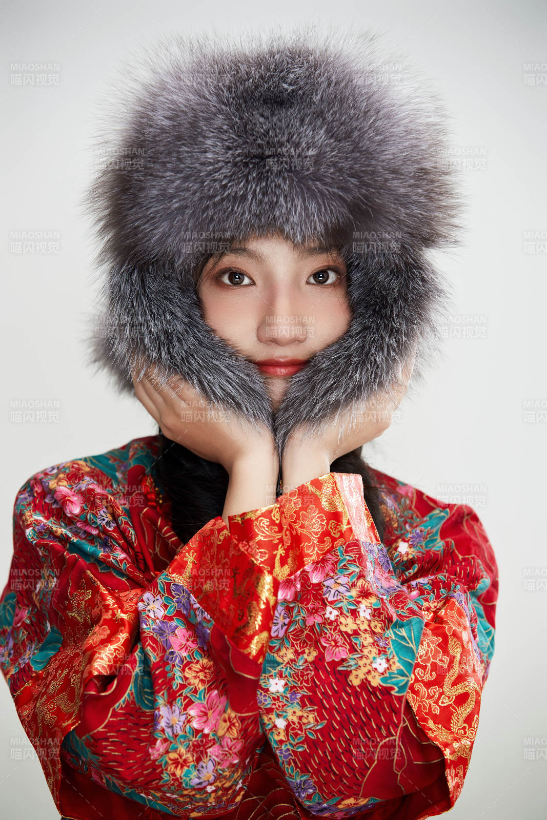 白色背景下穿中國傳統服飾頭戴絨帽的少女