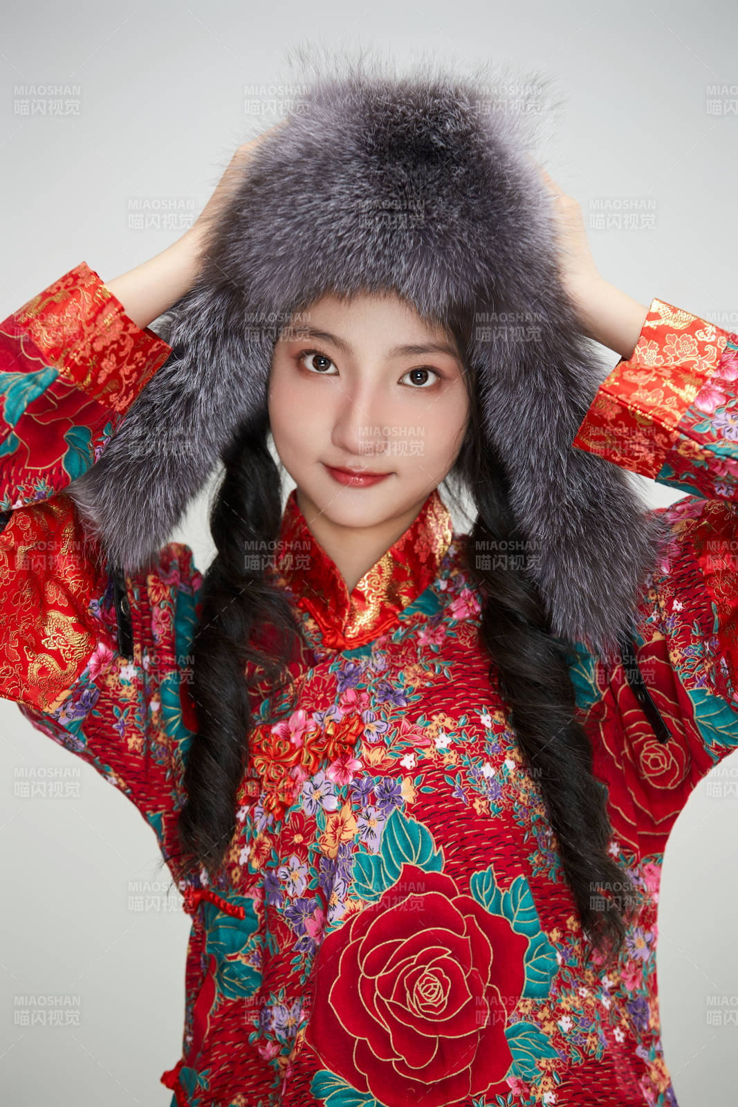 白色背景下穿中國傳統服飾頭戴絨帽的少女