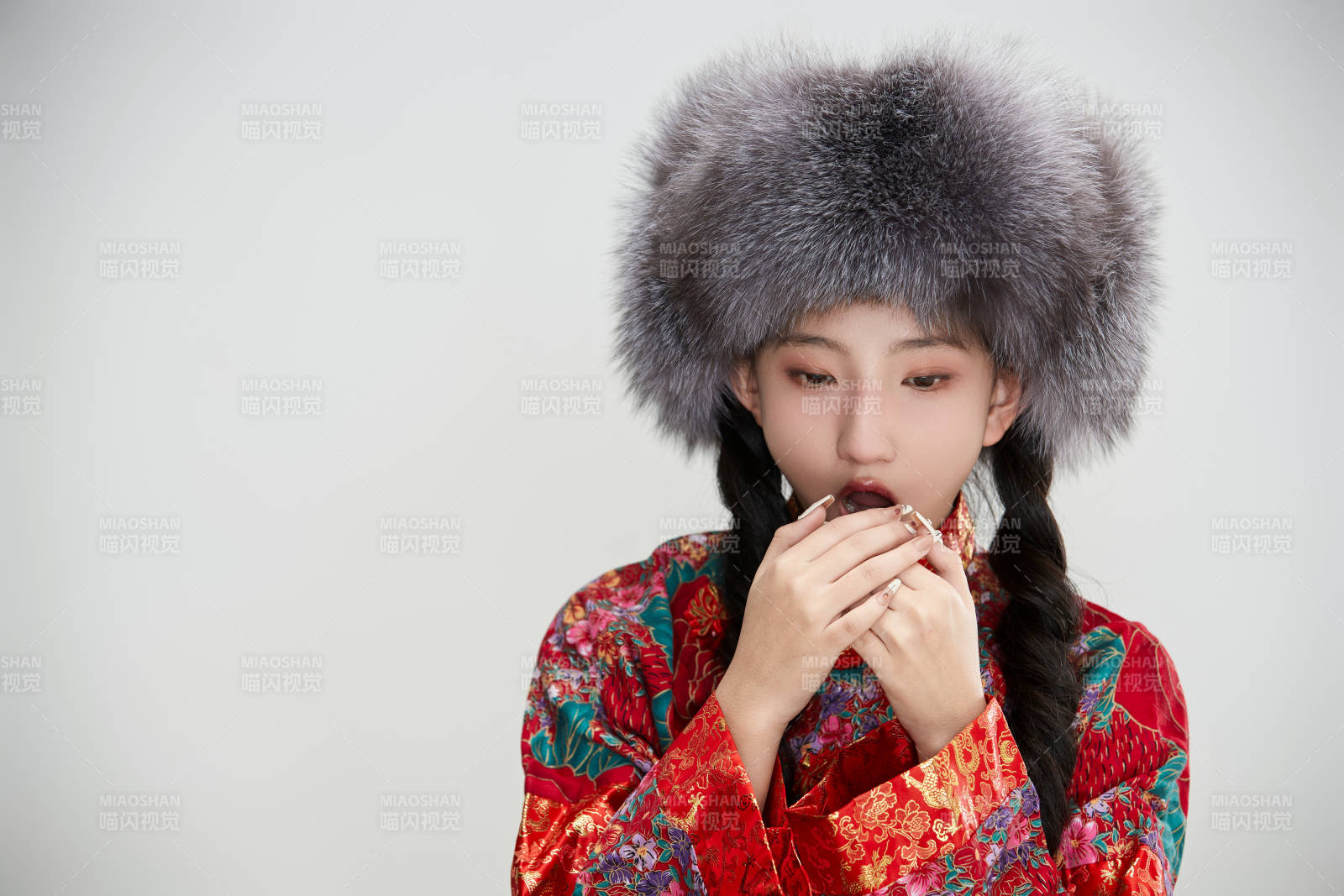 白色背景下穿中國傳統服飾頭戴絨帽的少女