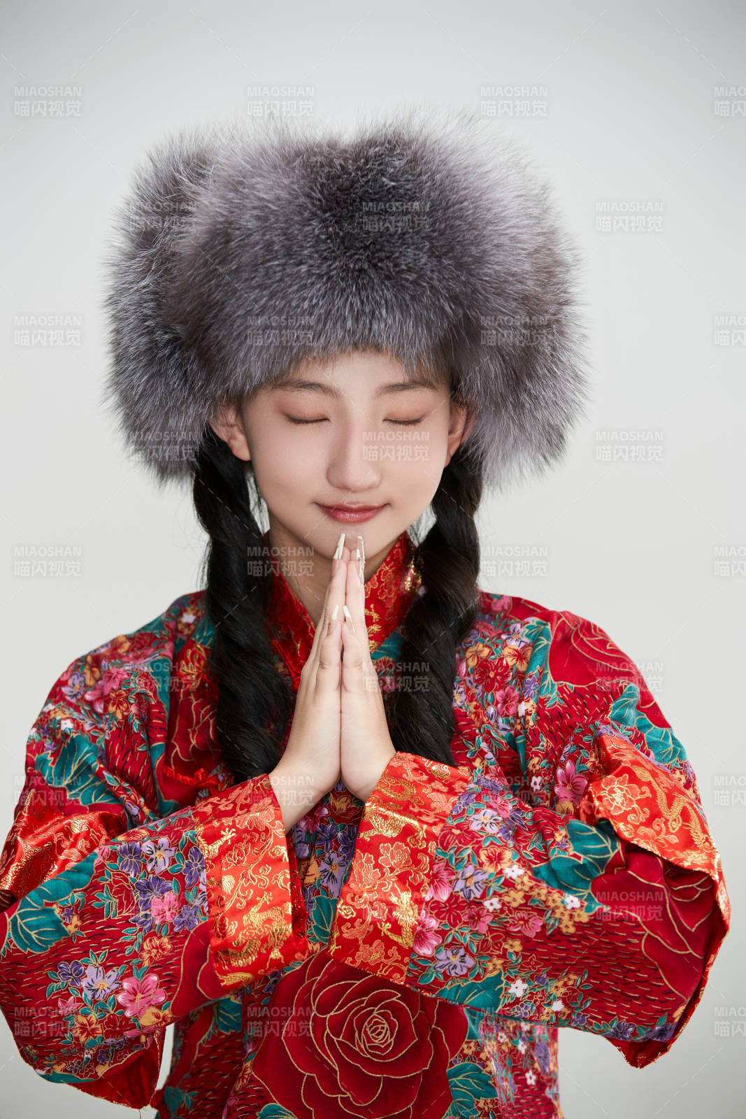 白色背景下穿中國傳統服飾頭戴絨帽的少女