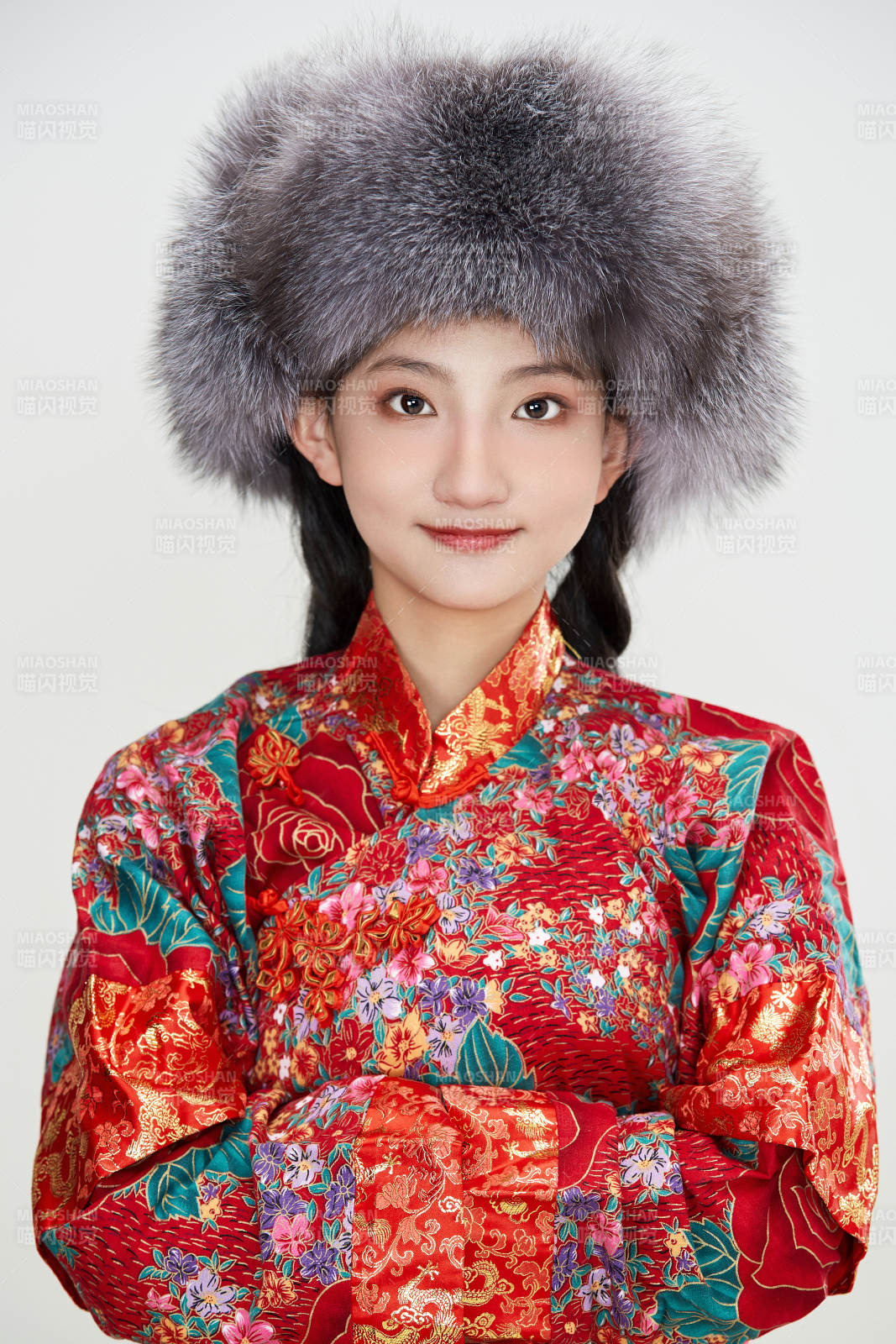 白色背景下穿中國傳統服飾頭戴絨帽的少女