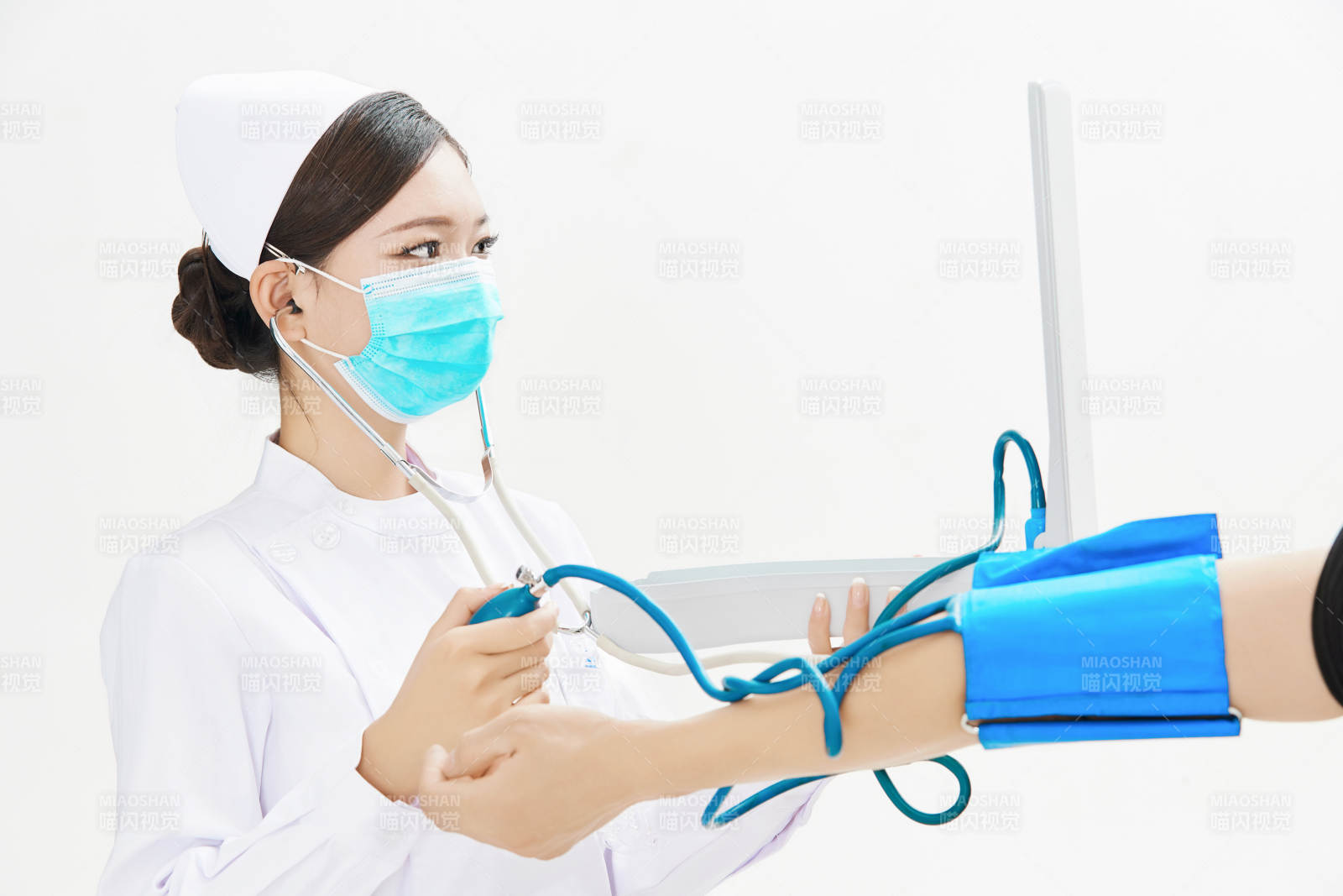 白色背景下手持血壓計為患者測量血壓的護士