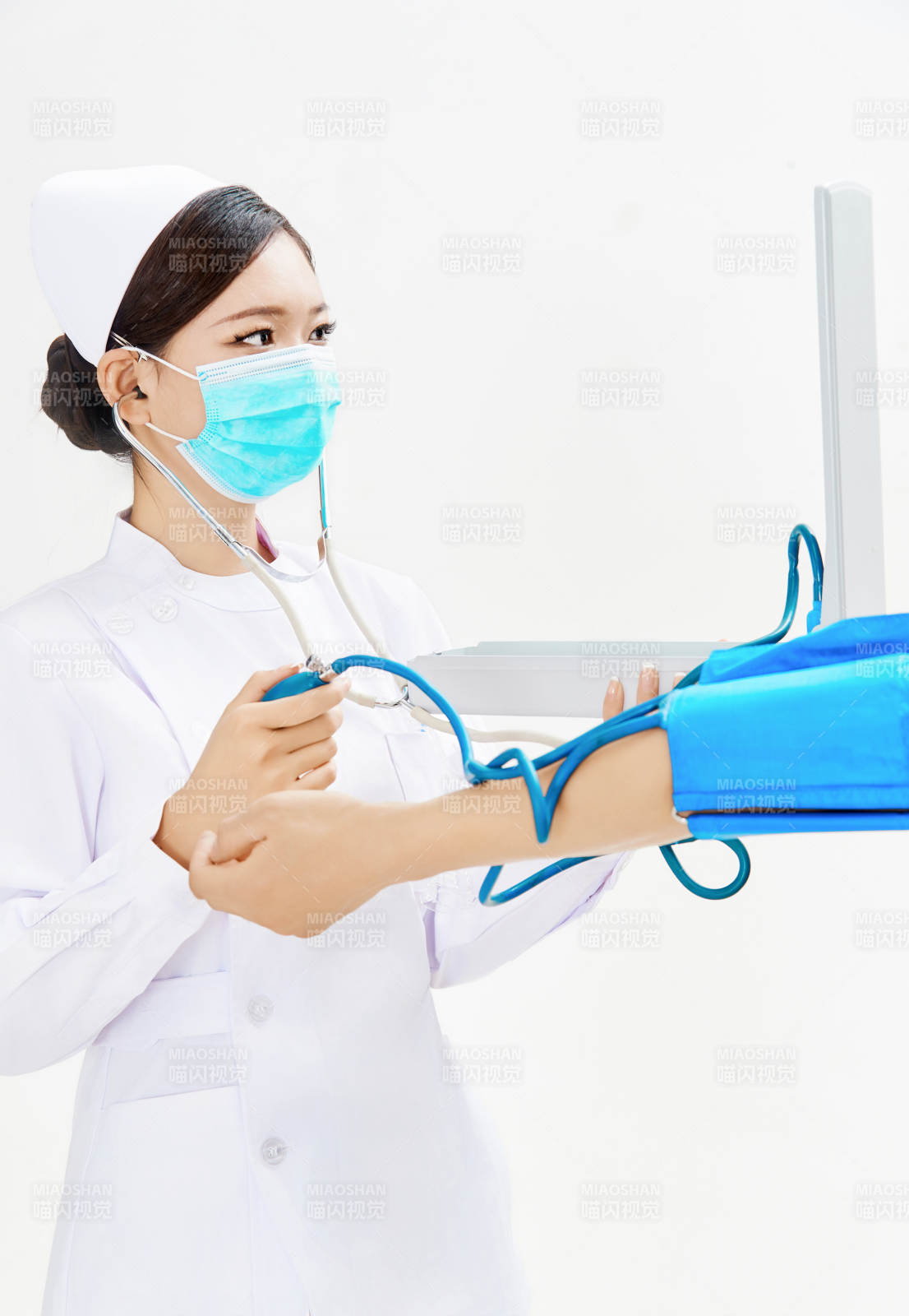 白色背景下手持血壓計為患者測量血壓的護士