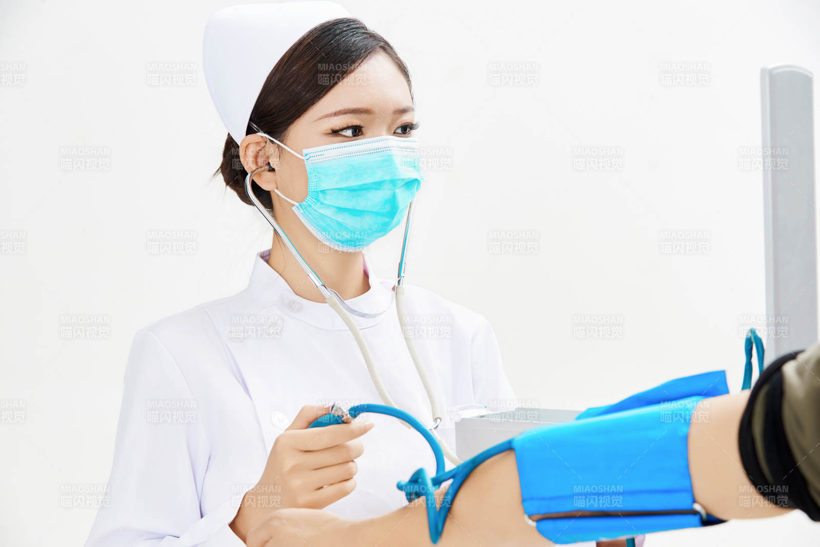 白色背景下手持血壓計(jì)為患者測(cè)量血壓的護(hù)士