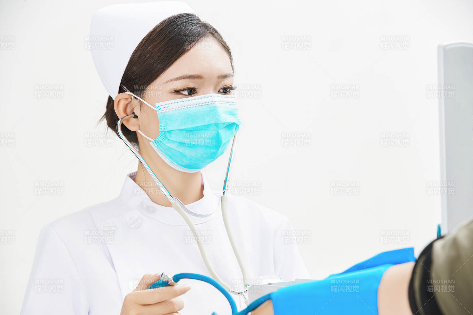 白色背景下手持血壓計為患者測量血壓的護士