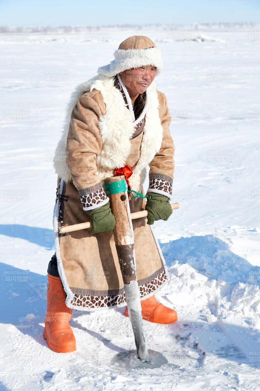 寒冷的冬季在冰凍的湖面上鑿冰捕魚的人們