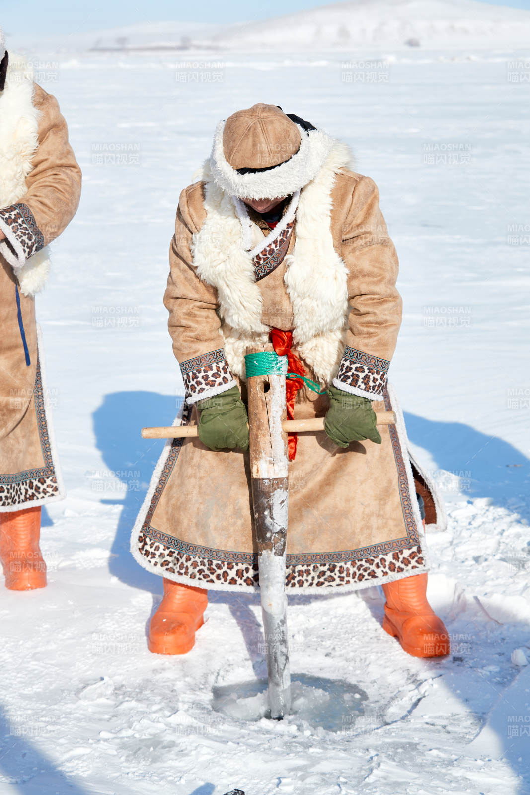 寒冷的冬季在冰凍的湖面上鑿冰捕魚的人們