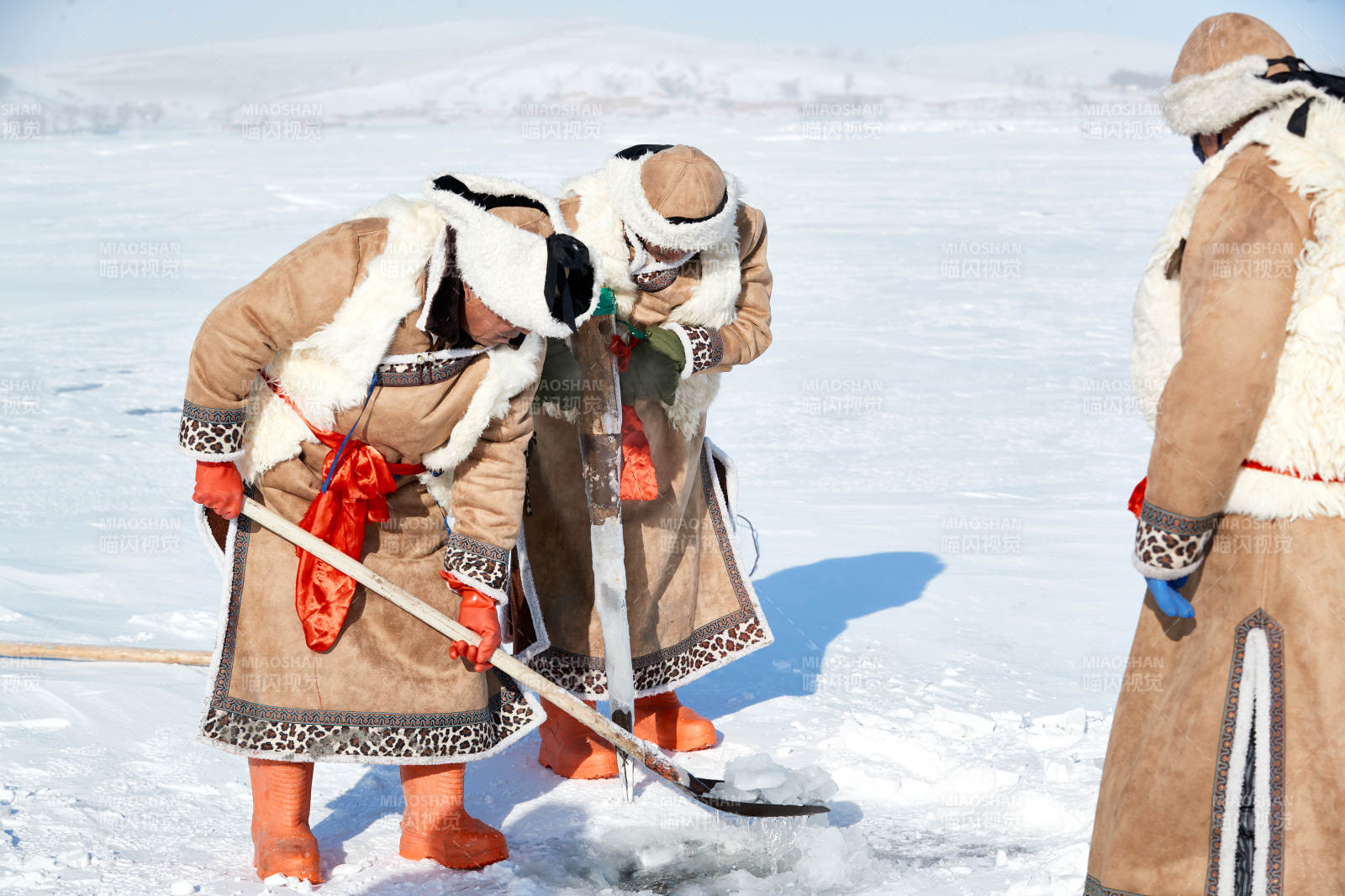 寒冷的冬季在冰凍的湖面上鑿冰捕魚的人們