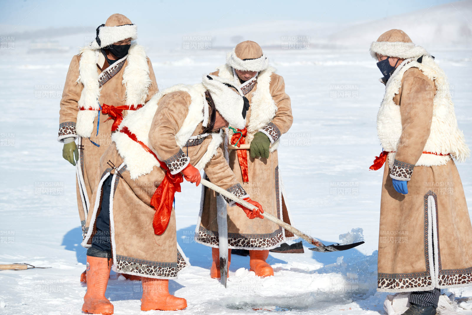 寒冷的冬季在冰凍的湖面上鑿冰捕魚的人們