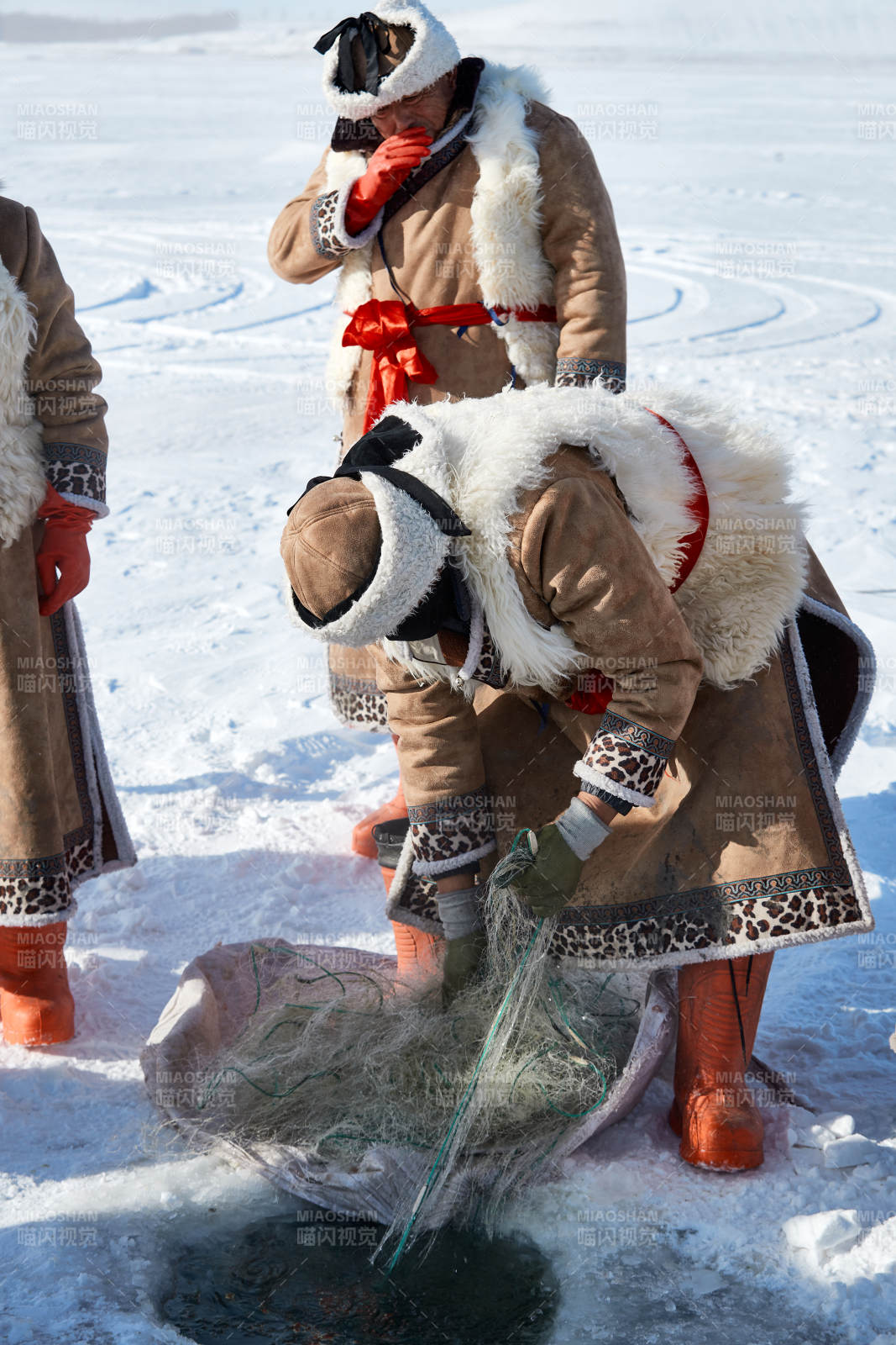 寒冷的冬季在冰凍的湖面上鑿冰捕魚的人們