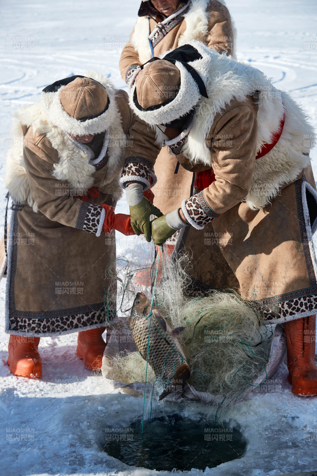 寒冷的冬季在冰凍的湖面上鑿冰捕魚的人們