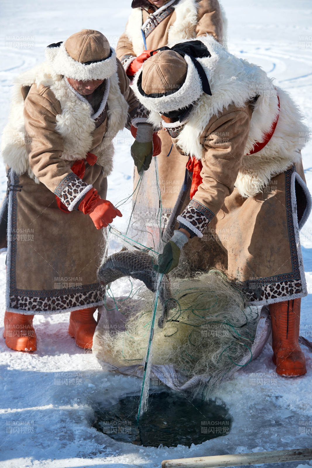 寒冷的冬季在冰凍的湖面上鑿冰捕魚的人們