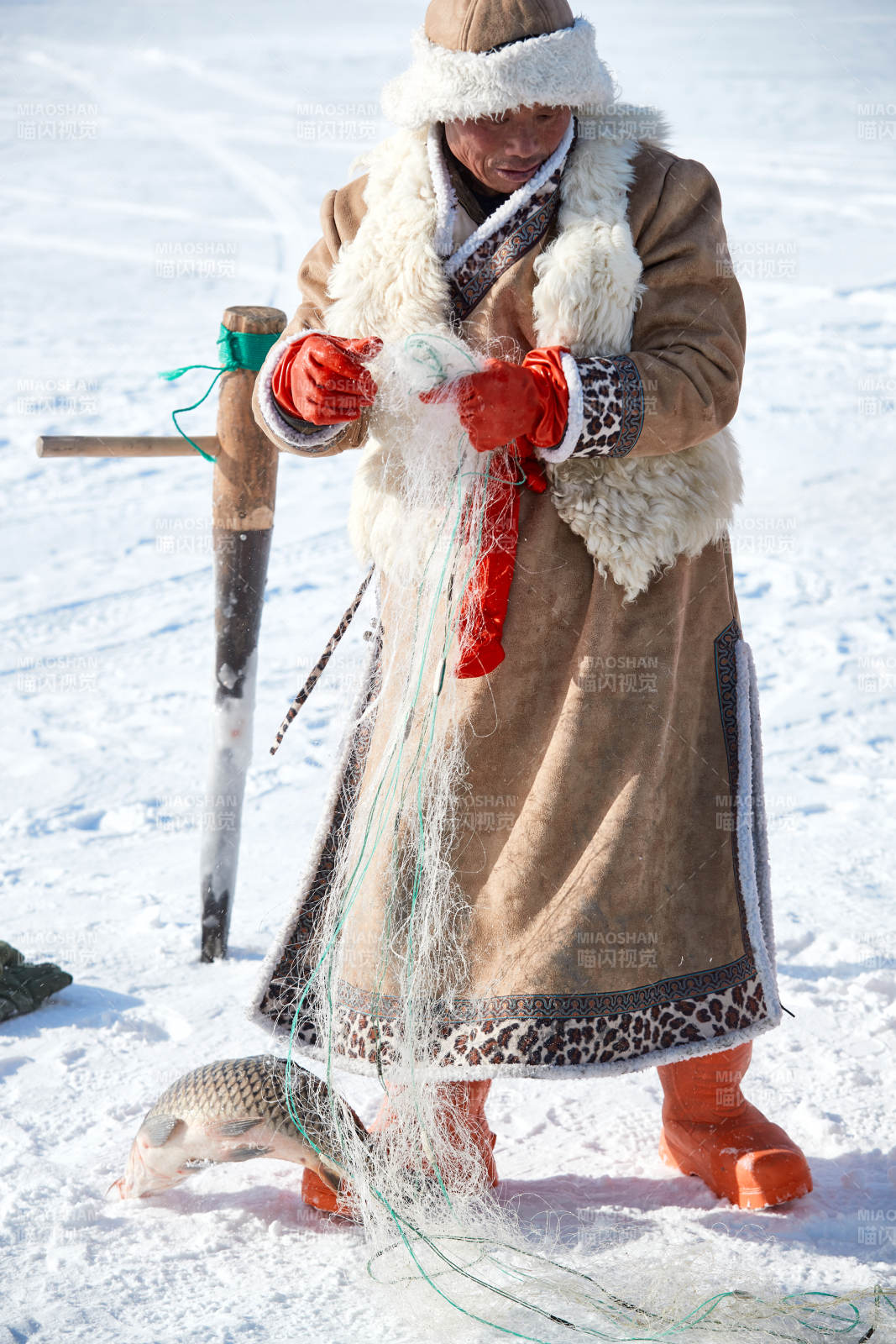 寒冷的冬季在冰凍的湖面上鑿冰捕魚的人們