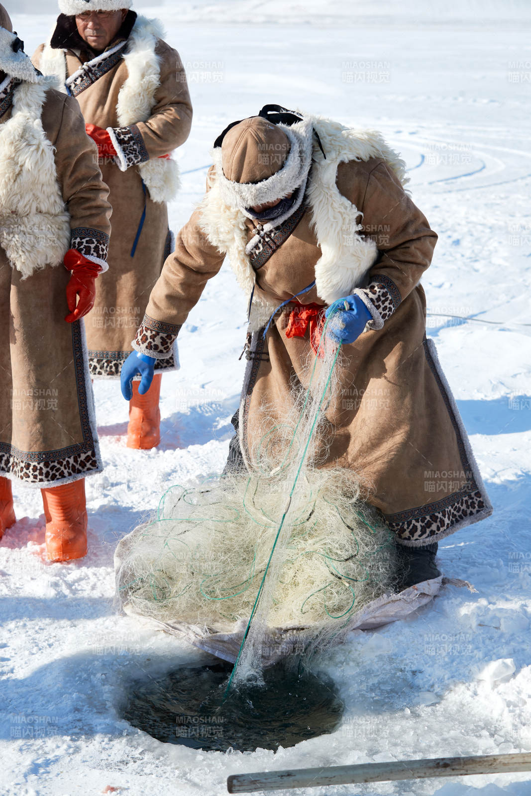 寒冷的冬季在冰凍的湖面上鑿冰捕魚的人們