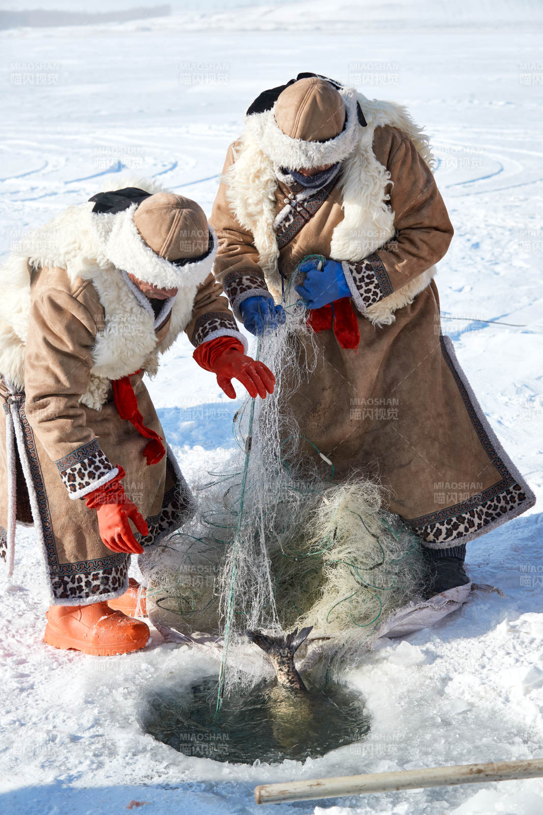 寒冷的冬季在冰凍的湖面上鑿冰捕魚的人們