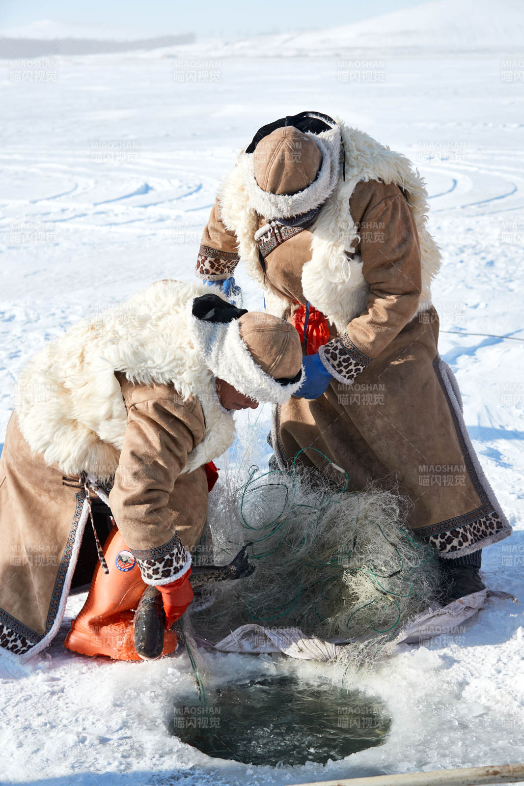 寒冷的冬季在冰凍的湖面上鑿冰捕魚的人們