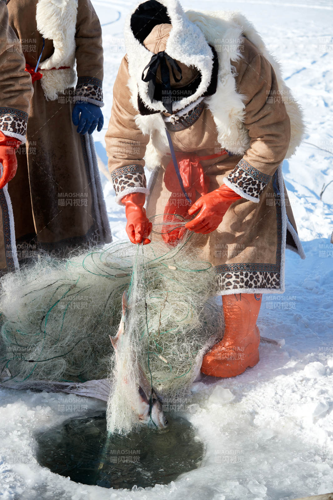 寒冷的冬季在冰凍的湖面上鑿冰捕魚的人們