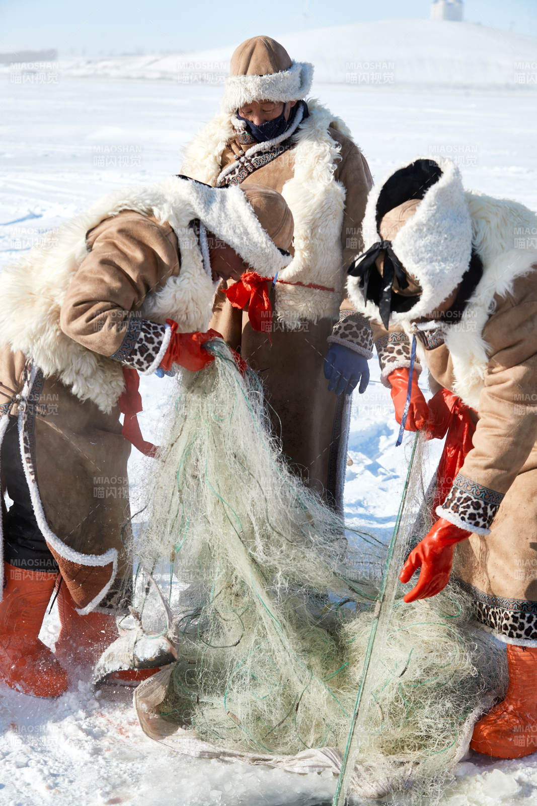 寒冷的冬季在冰凍的湖面上鑿冰捕魚的人們