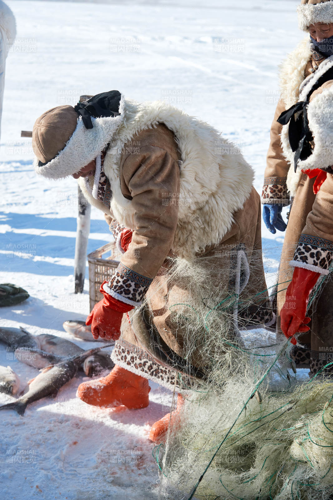 寒冷的冬季在冰凍的湖面上鑿冰捕魚的人們