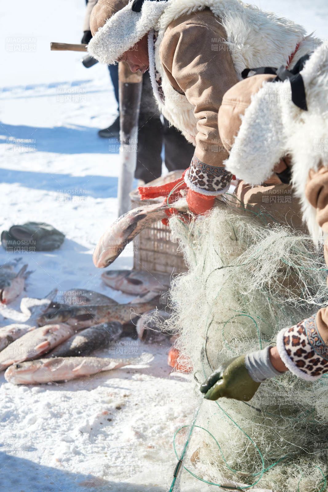 寒冷的冬季在冰凍的湖面上鑿冰捕魚的人們