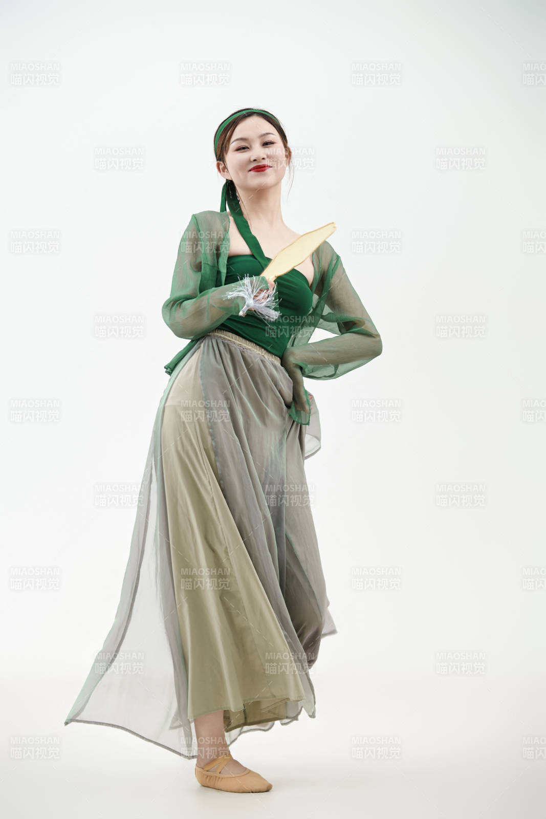 身穿青色古典舞蹈服裝手拿蒲扇跳舞的少女