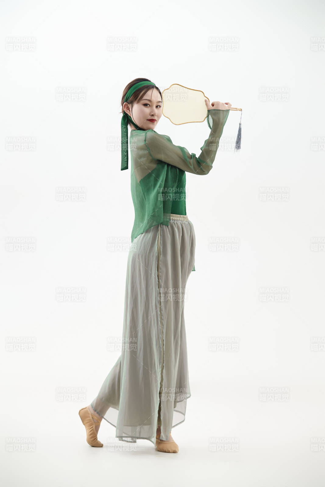 身穿青色古典舞蹈服裝手拿蒲扇跳舞的少女