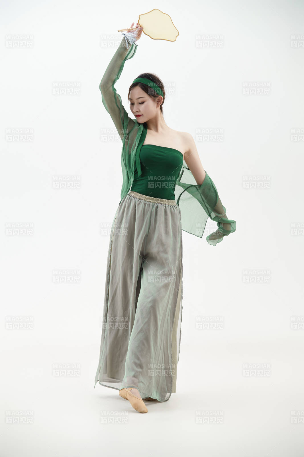 身穿青色古典舞蹈服裝手拿蒲扇跳舞的少女