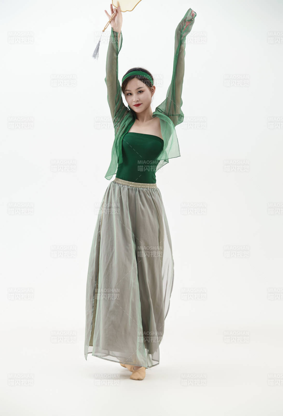 身穿青色古典舞蹈服裝手拿蒲扇跳舞的少女