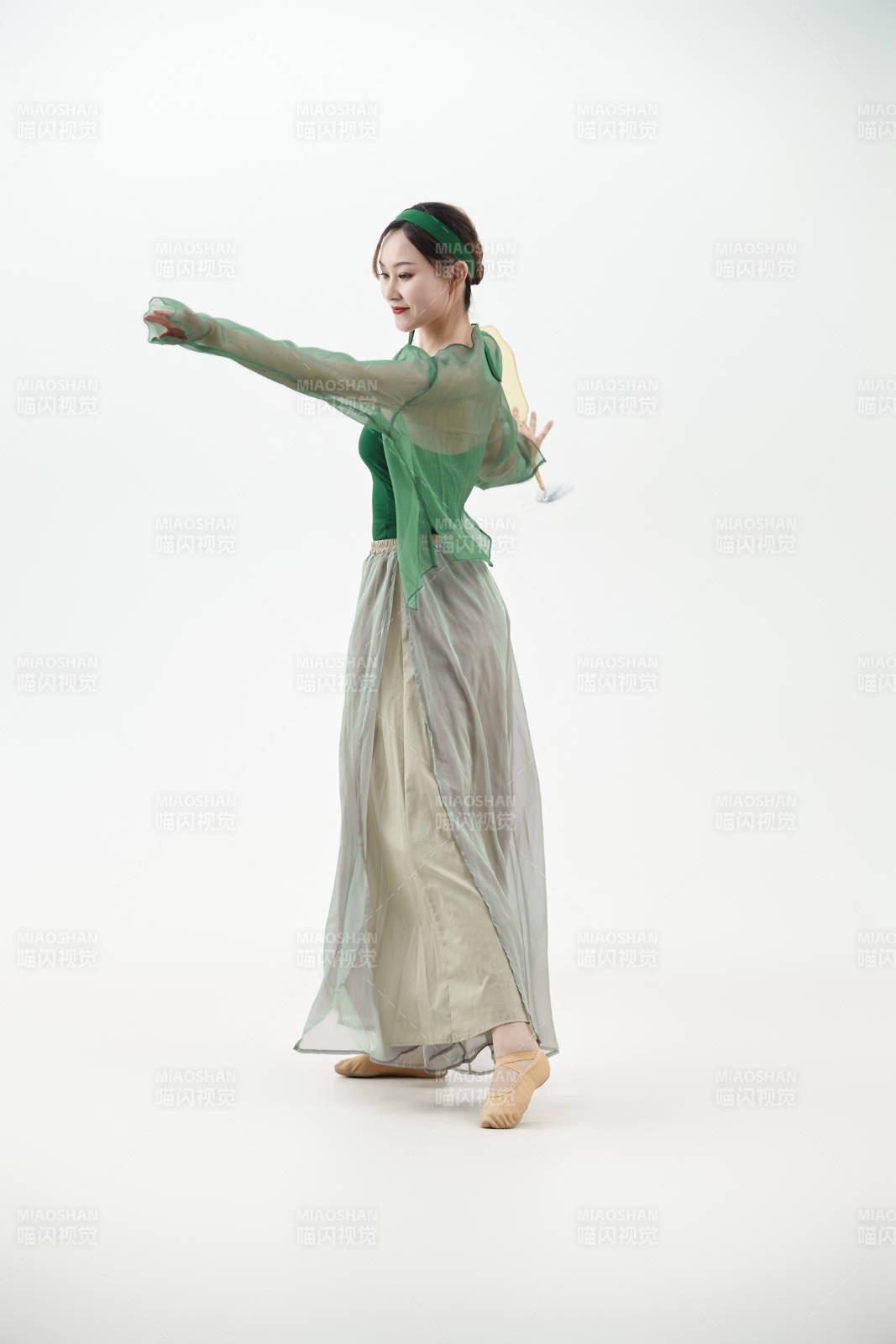 身穿青色古典舞蹈服裝手拿蒲扇跳舞的少女