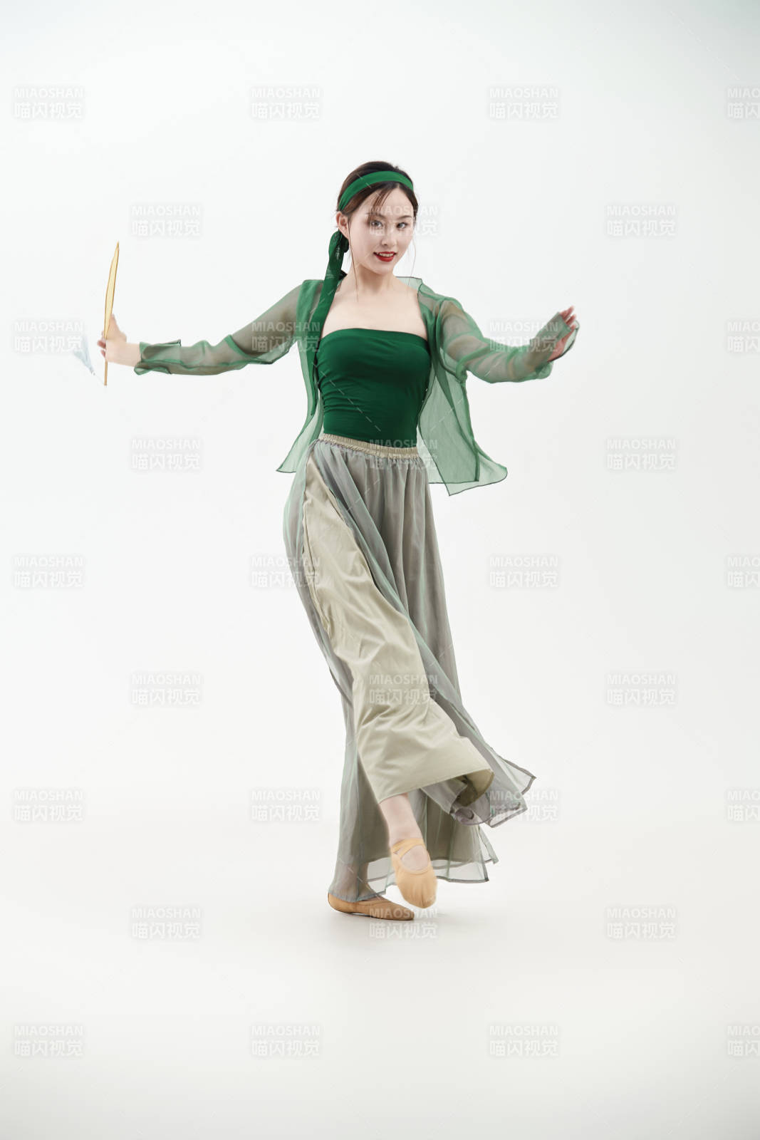 身穿青色古典舞蹈服裝手拿蒲扇跳舞的少女