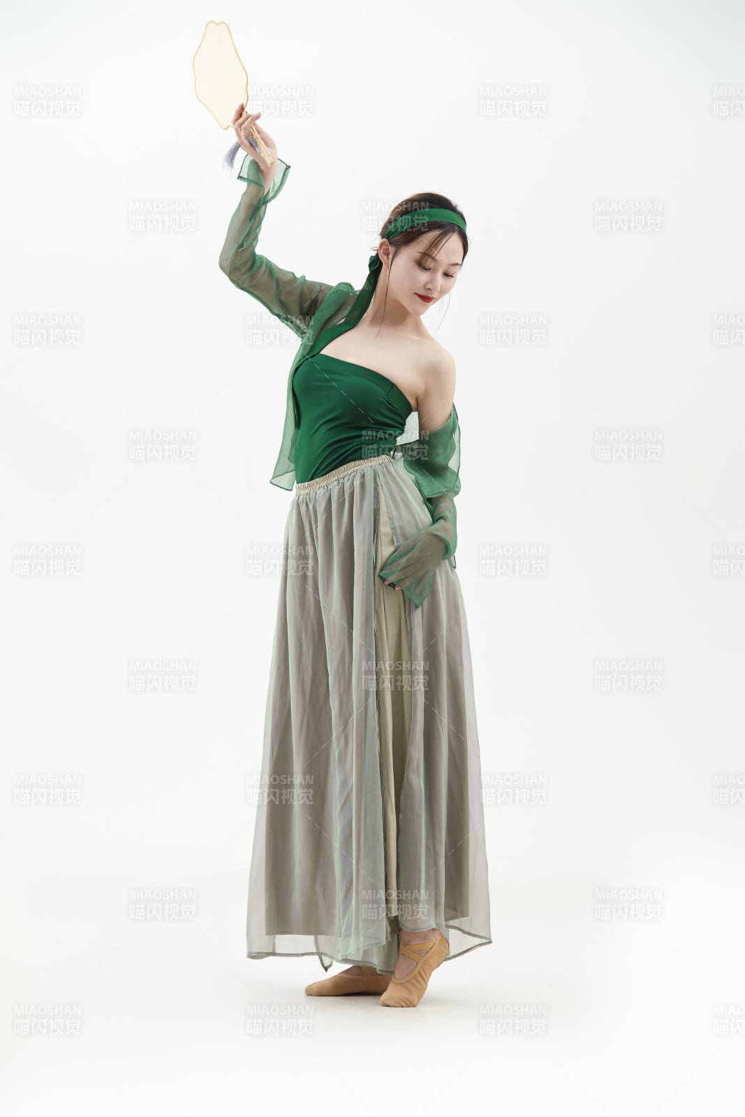 身穿青色古典舞蹈服裝手拿蒲扇跳舞的少女