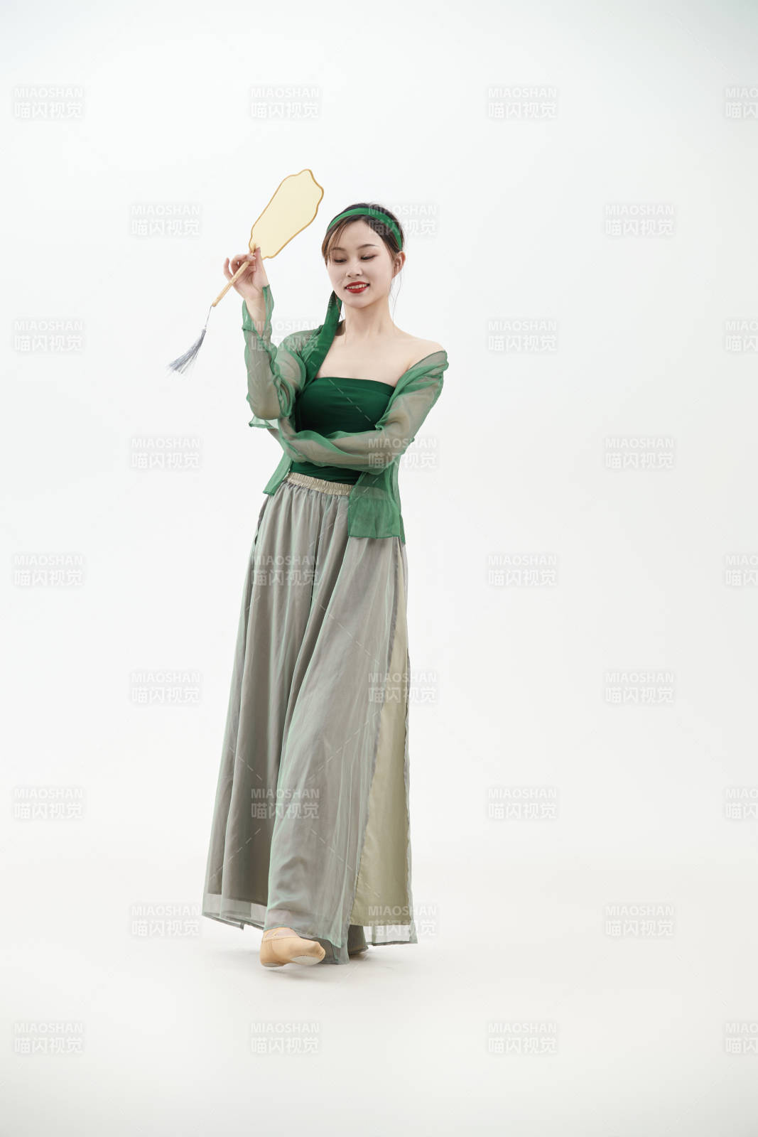 身穿青色古典舞蹈服裝手拿蒲扇跳舞的少女